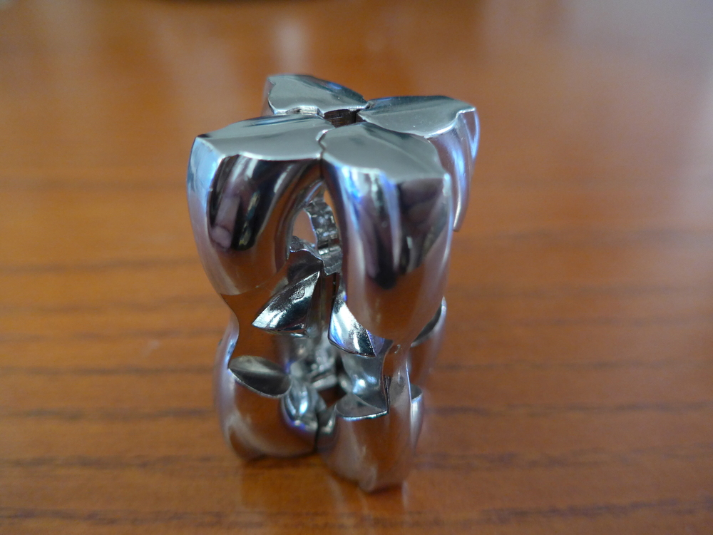 I got this really nice puzzle from Tim van Erven. It is made of metal. Its two parts can move relative to each other through shaped holes and slits.